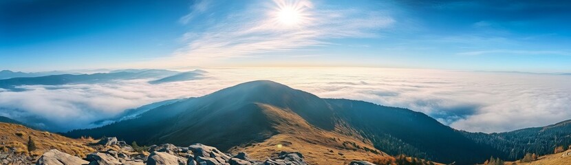 Panoramic view of Carpathian Mountains with foggy valley and sunlight on mountain peak under vibrant blue sky with clouds, wide high-resolution morning landscape background