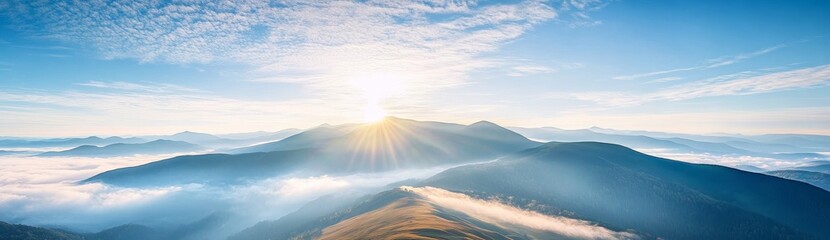 Panoramic view of Carpathian Mountains with foggy valley and sunlight on mountain peak under vibrant blue sky with clouds, wide high-resolution morning landscape background
