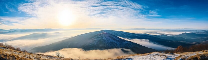 Panoramic view of Carpathian Mountains with foggy valley and sunlight on mountain peak under vibrant blue sky with clouds, wide high-resolution morning landscape background