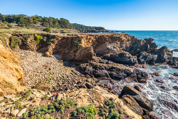 Coastal cliffs along California's Highway 1 in Northern California. Rugged ocean rocks, crashing waves, and a colorful sky create a breathtaking Pacific Coast landscape