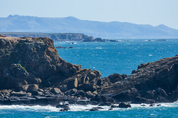 Coastal cliffs along California's Highway 1 in Northern California. Rugged ocean rocks, crashing waves, and a colorful sky create a breathtaking Pacific Coast landscape