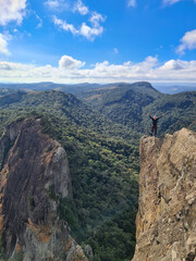 White-haired man on top of mountain in region covered in native forest
