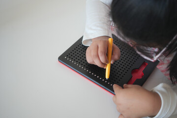 Child Engaging with Magnetic Dot Drawing Board for Creative Play