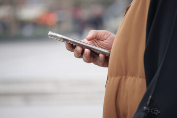 Person checking phone while standing outdoors in a busy area