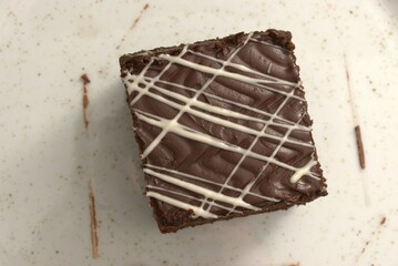 Chocolate brownie with icing on white background – homemade dessert and sweet treat concept