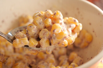 Creamy corn salad with spices in a serving spoon