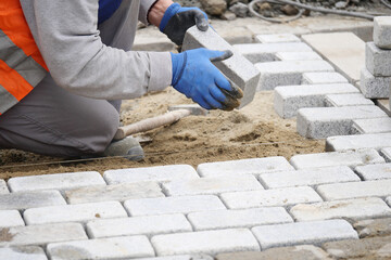Worker installing stone pavers on a construction site