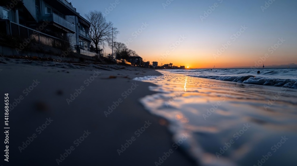 Leinwandbilder a low-angle shot captures a tranquil beach at dusk featuring gentle waves reflecting the setting sun