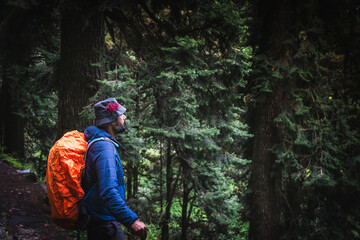 A trekker with hiking backpack on beautiful mountain landscape background. Climber hike to mountains. Hikers walking in mountain in monsoon season	