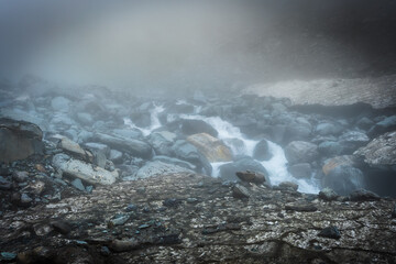 Glacial river flowing under snow bridge in the Himalayas, Himachal Pradesh

