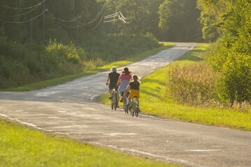 Fototapeta premium Group Cycling Along a Scenic Road During a Sunny Summer Day