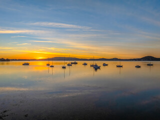 Naklejka premium Sunrise with high cloud, boats and reflections over the water