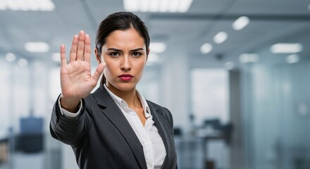 Confident businesswoman signaling stop with hand in modern office  