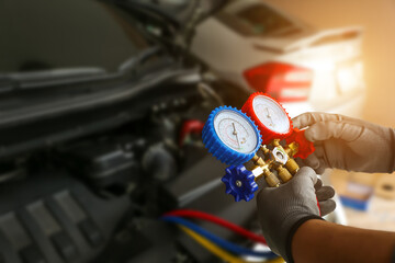 Car mechanic repairman holding air refrigerant meter manifold gauge for car care maintenance...