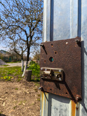 A rusty metal latch on the side of a metal door