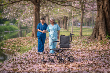 Nurse caregiver with elderly woman enjoying beneath blooming trees. suggesting in healthcare...