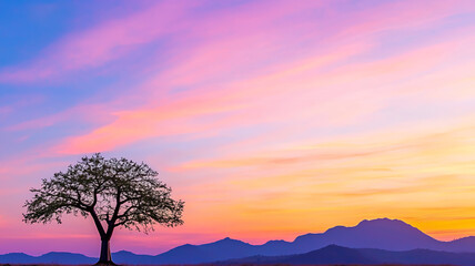 Obraz premium solitary tree stands against vibrant sunset sky, showcasing hues of pink, orange, and purple, with mountains in background