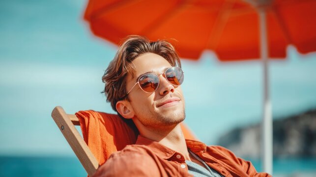 A relaxed young man enjoying the sun and vacation at the beach under an umbrella.
