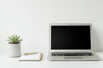 Minimalist workspace with a laptop, notebook, pen, and succulent plant on a white desk.