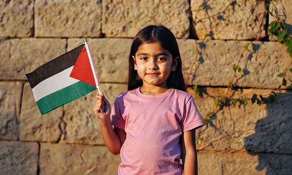 Young girl holding Palestine flag against old stone wall.
