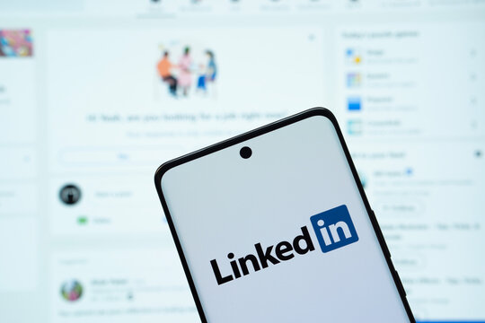 Dhaka, Bangladesh - 17 March 2025: The logo of the linked in is displayed on a smartphone screen, and the website linked in is visible on a computer screen in the background.