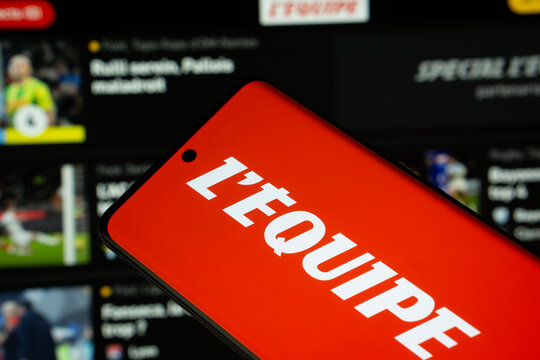 Dhaka, Bangladesh - 17 March 2025: The logo of the newspaper L'&Eacute;quipe is displayed on a smartphone screen, and the website le quipe is visible on a computer screen in the background.