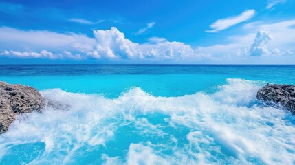 Obraz premium Turquoise ocean waves crashing on rocks under a clear sky
