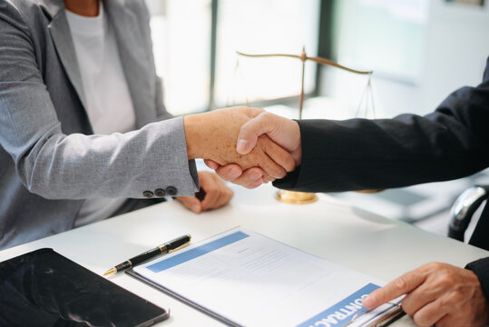 Woman lawyer hand and women client shaking hand collaborate on working agreements with contract documents