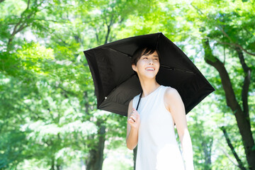 緑の中でスキンケアをするショートヘアの若い女性