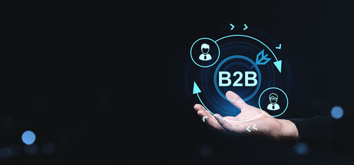 Business-to-business B2B digital concept with icons and network symbols above a hand on a dark creative background representing corporate communication.