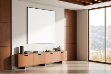 Modern interior with blank square poster mockup on white wall above wooden sideboard in minimalist living room flooded with natural light from large window. 3D Rendering