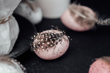 Close-up of pastel pink Easter egg with feather. Speckled festive decor detail for spring design projects