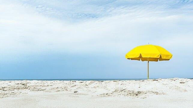 Yellow beach umbrella on sandy shore, calm ocean.