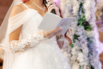 The bride reading her vows into a microphone at the wedding ceremony. Happy bride speaking wedding...