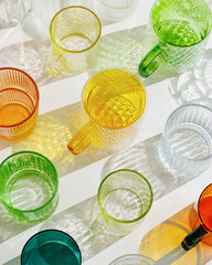 Colored Glasses pattern with shadow and sunlight reflection on white background, minimal aesthetic top view summer still life, refraction at shine drink, caustic effect, orange blue glass cups