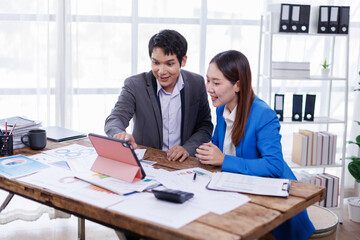 Successful business people giving each other a high five in a meeting. Two young asian business professionals celebrating teamwork in an office.
