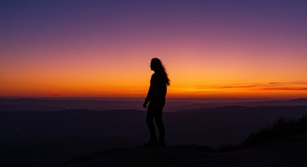 Silhouette of a Person with Long Hair Watching Sunset Over a Mountain Landscape
