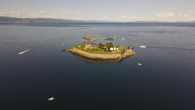 Munkholmen (Monk's islet) island surrounded by serene blue waters with boats in Trondheim, Norway