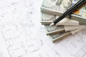 Big amount of US dollars money bills with pen and planning blueprints of residential building...