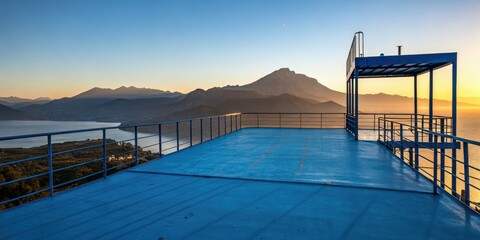 Obraz premium Minimalist sunset landscape: silhouetted mountains viewed from a blue platform, serene and simple.