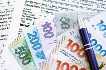 Argentine pesos money bills in big amount lies on table with pen and tax forms close up