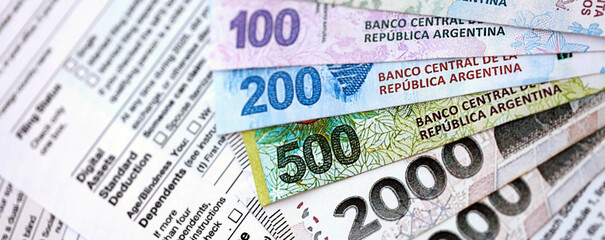 Argentine pesos money bills in big amount lies on table with pen and tax forms close up