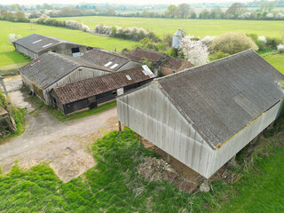 Aerial view of a large and mainly derelict dairy farm seen in rural Britain. Notice the tall grain...