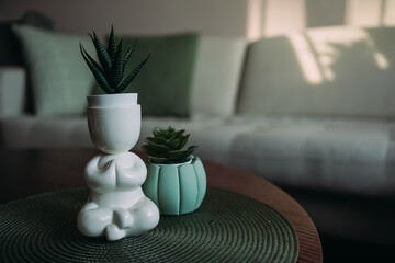 two unique plant green pot and lotus pose figure with green houseplants on the table