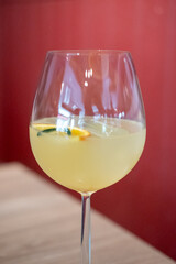 A glass of citrus sangria, featuring a vibrant orange hue with ice and a slice of fruit garnish