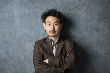 ジャケットを着て腕組みをする笑顔の男性　カメラ目線　真剣な表情