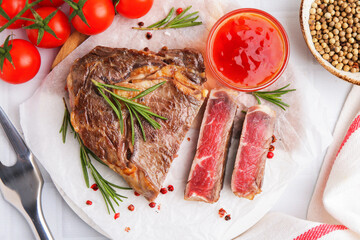 Pieces of delicious beef meat, spices, tomatoes and fork on white table, flat lay