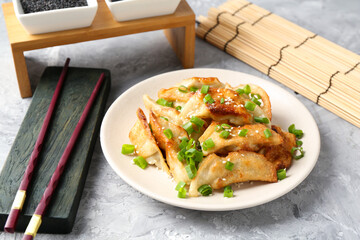 Tasty fried gyoza (dumplings) and chopsticks on light grey table