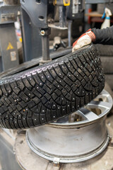 Professional mounting of a studded winter tire on an aluminium wheel in the garage. Seasonal tire...