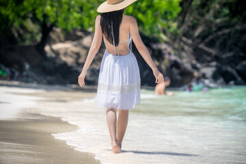 Woman tourist in dress play around at the edge of the sea beach, enjoy moment of the woman in summer trip